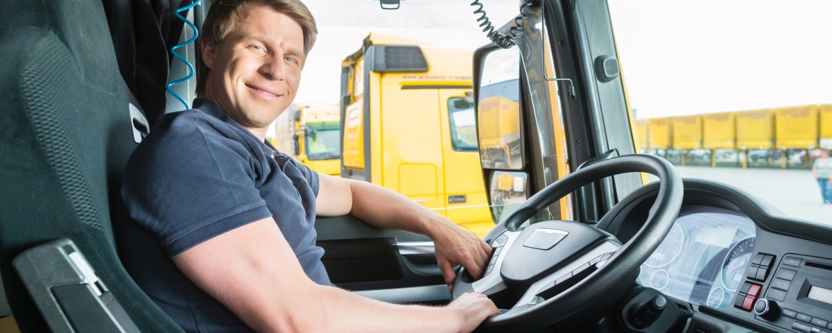 Logistics - proud driver or forwarder in drivers cap of truck and trailer, on a transshipment point